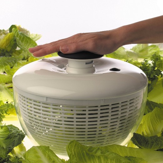 Hand on top of an OXO salad spinner. Lettuce is in the background.