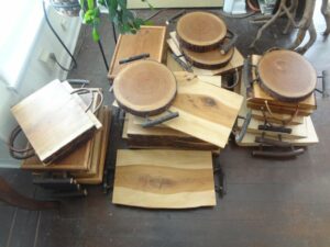 dozens of custom made cutting boards of different shapes, sizes, woods, and heights