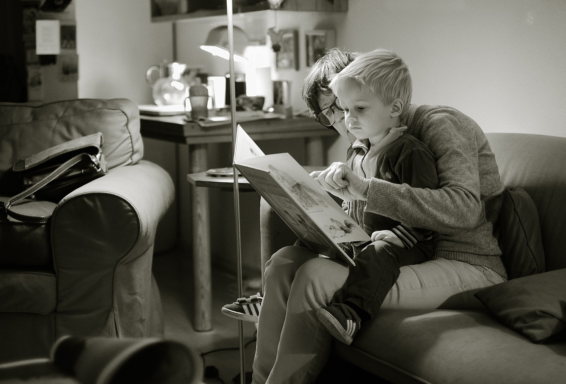 An adult woman reading a book to a small child.