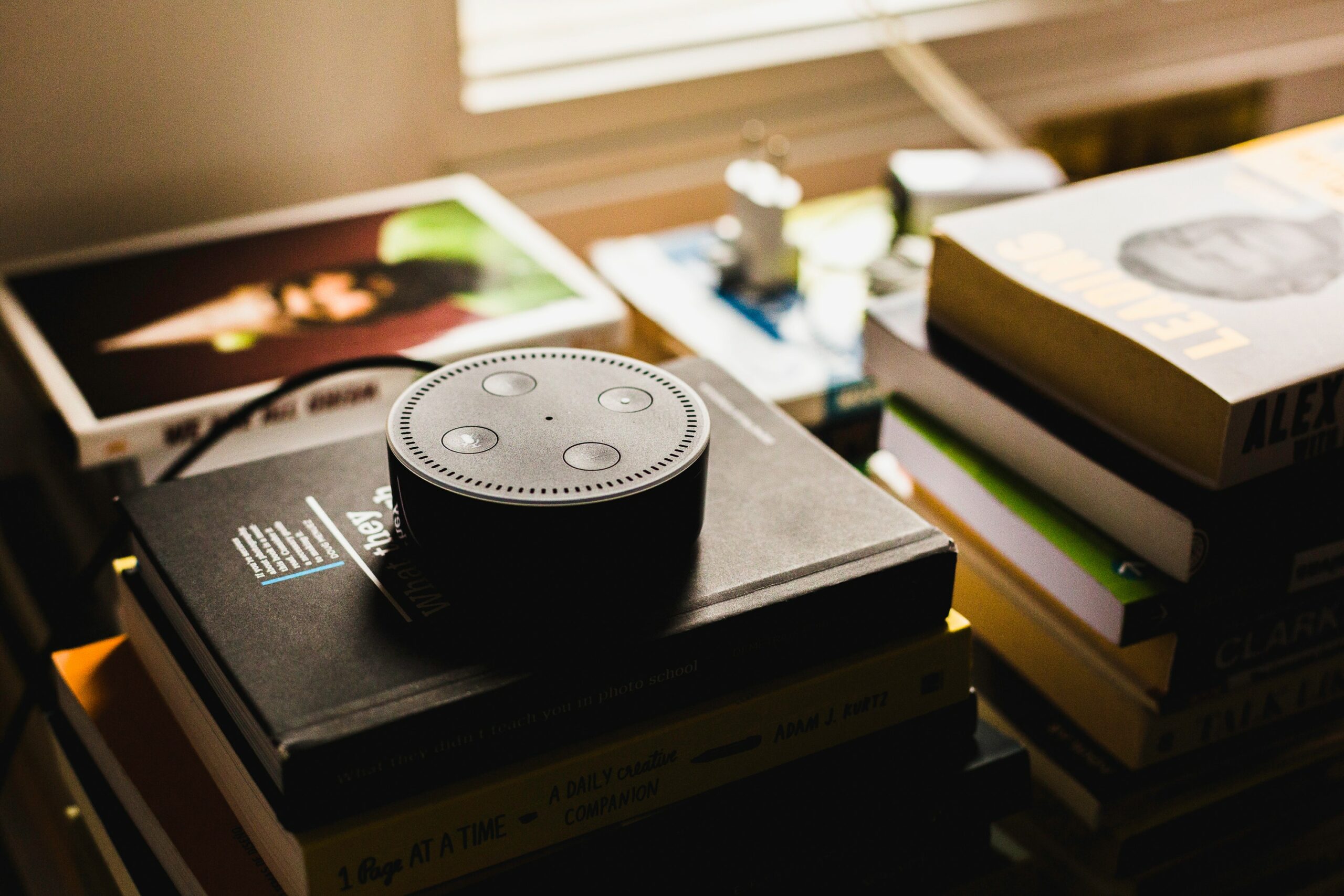 Amazon Alexa Echo Dot resting on a stack of books.