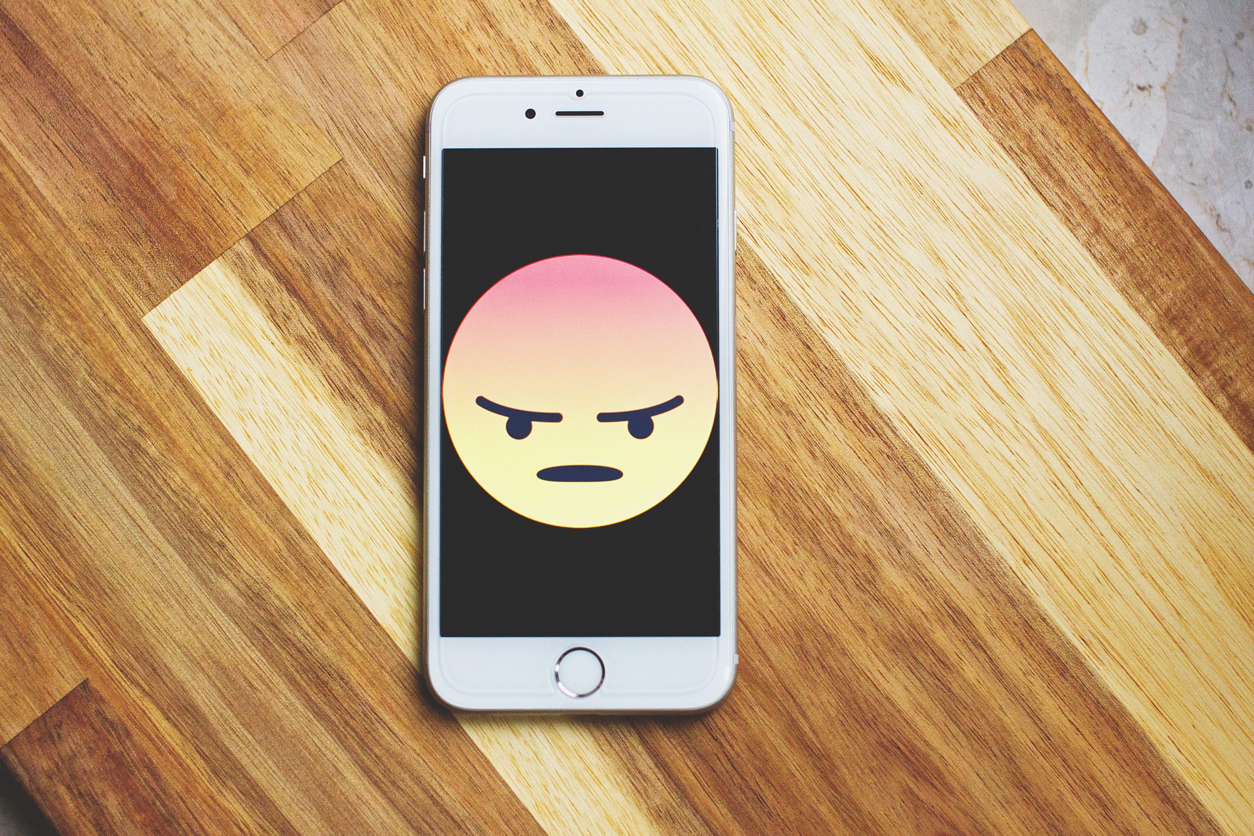 Smart phone displaying the angry face emoji