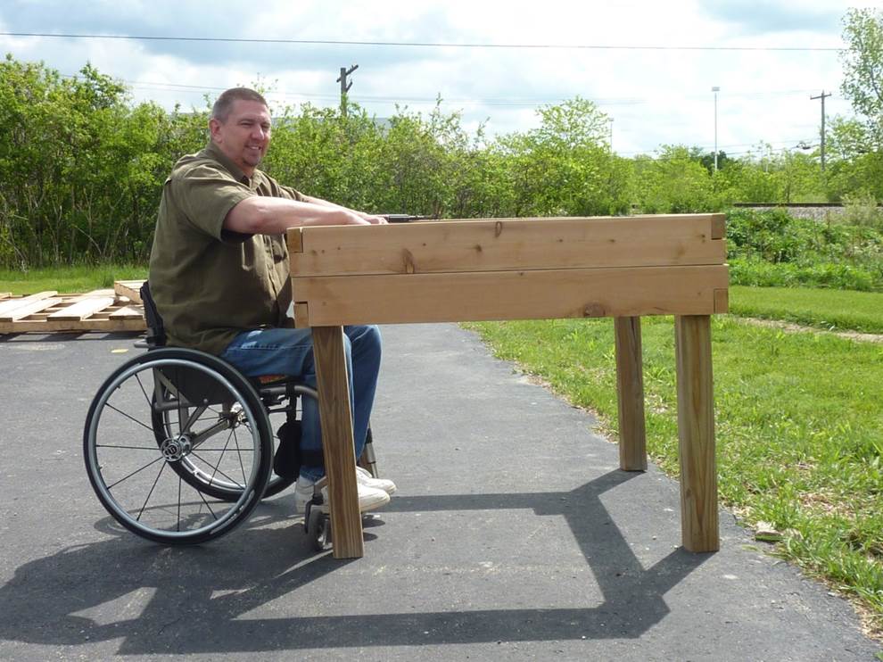 A man using a wheelchair with a raised bed that he can pull his wheelchair under--a tabletop raised bed