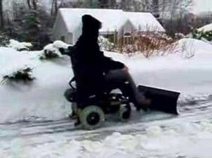 Person in powerchair with snow plow attached to front