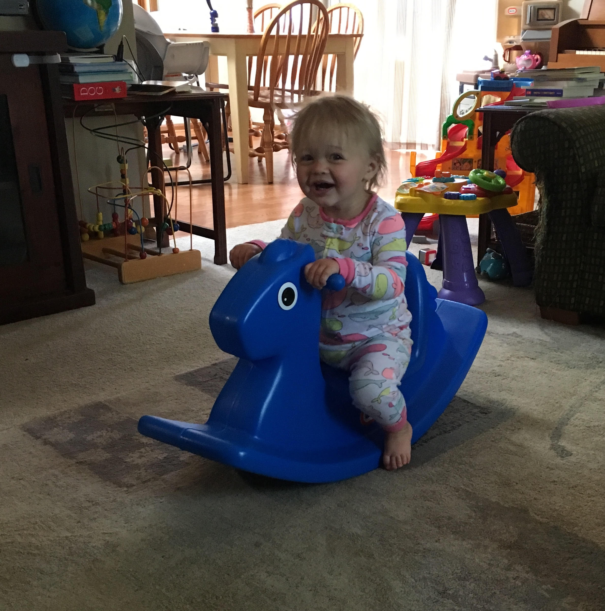 a toddler on a rocking horse with toys in the background